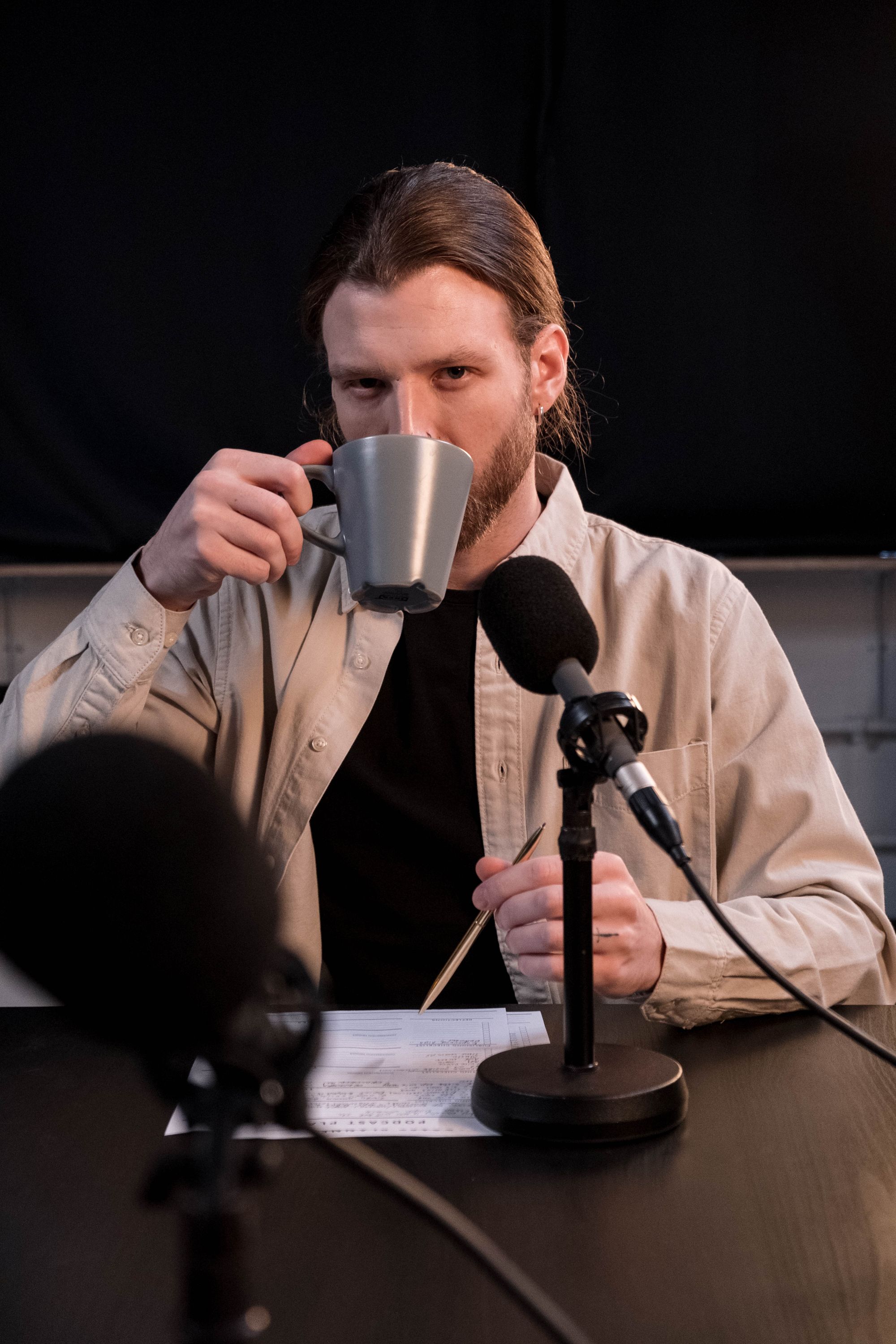 Un podcaster con una tazza davanti al microfono