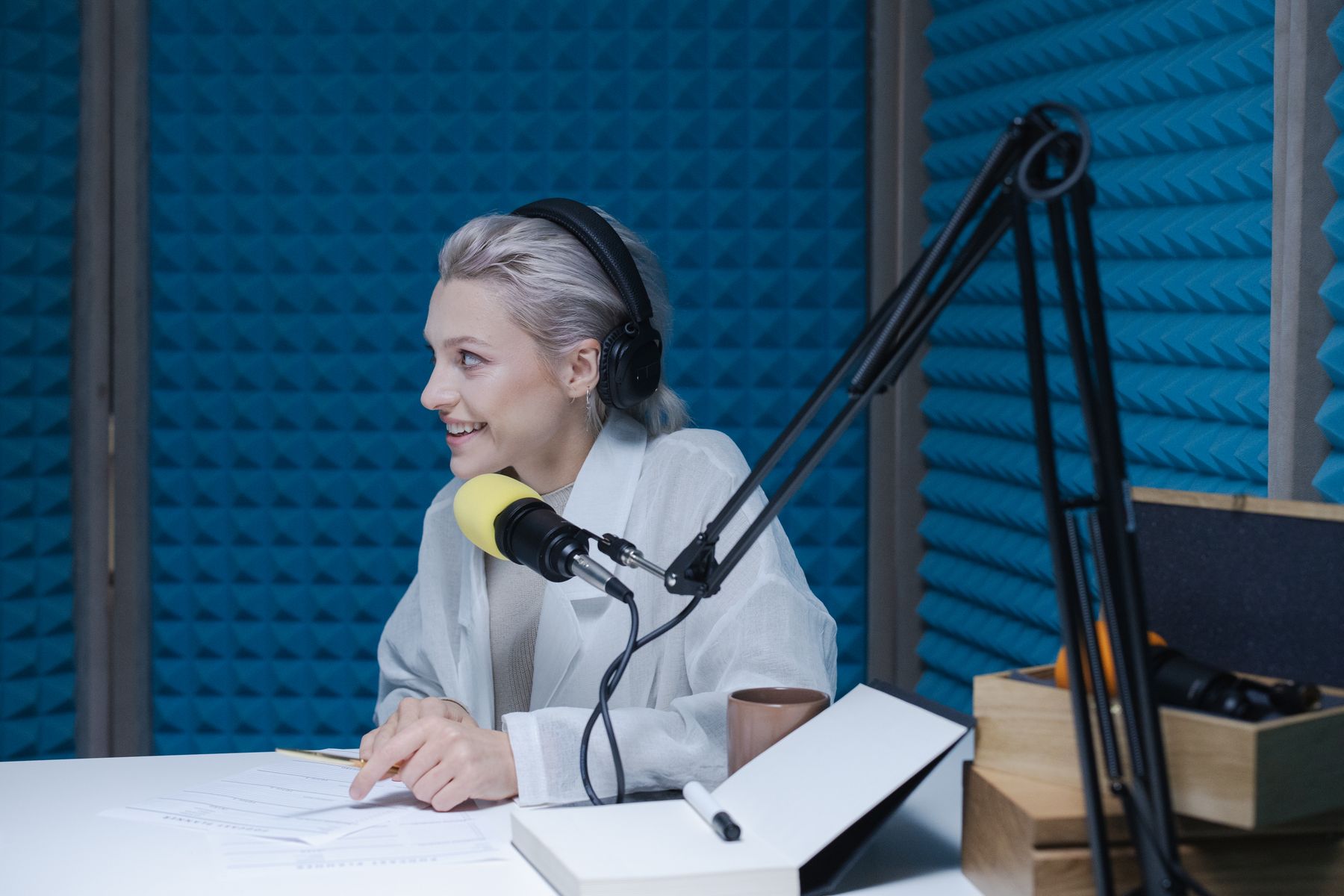 Una relatrice con cuffie e microfono in uno studio blu